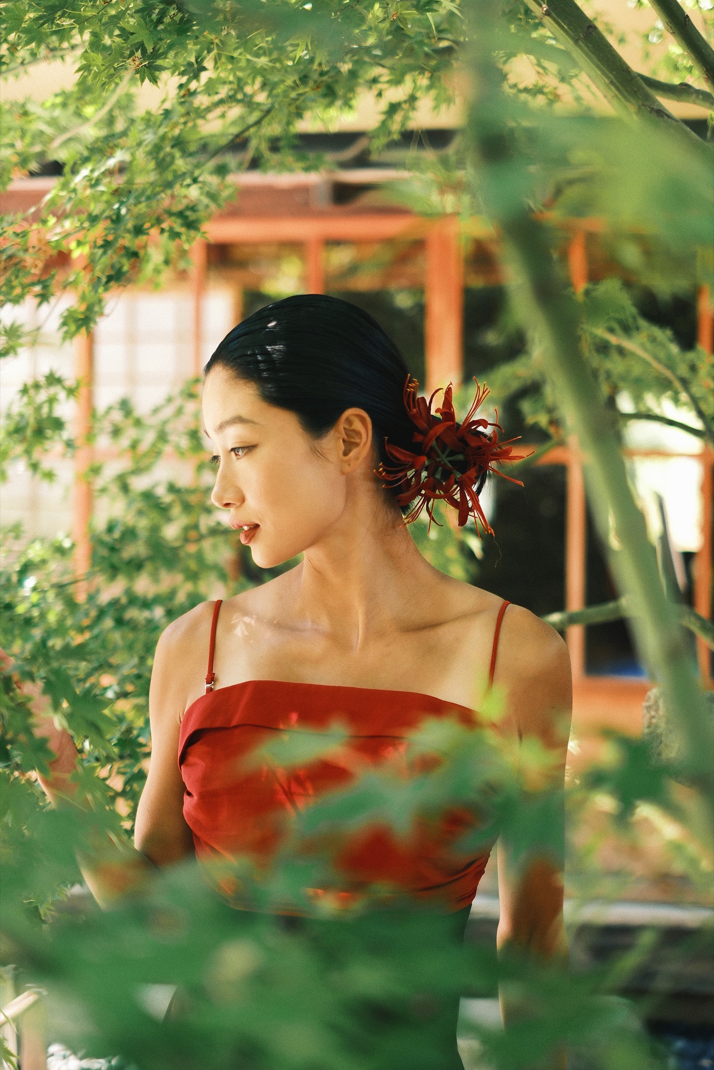 A woman in a red dress surrounded by green leaves