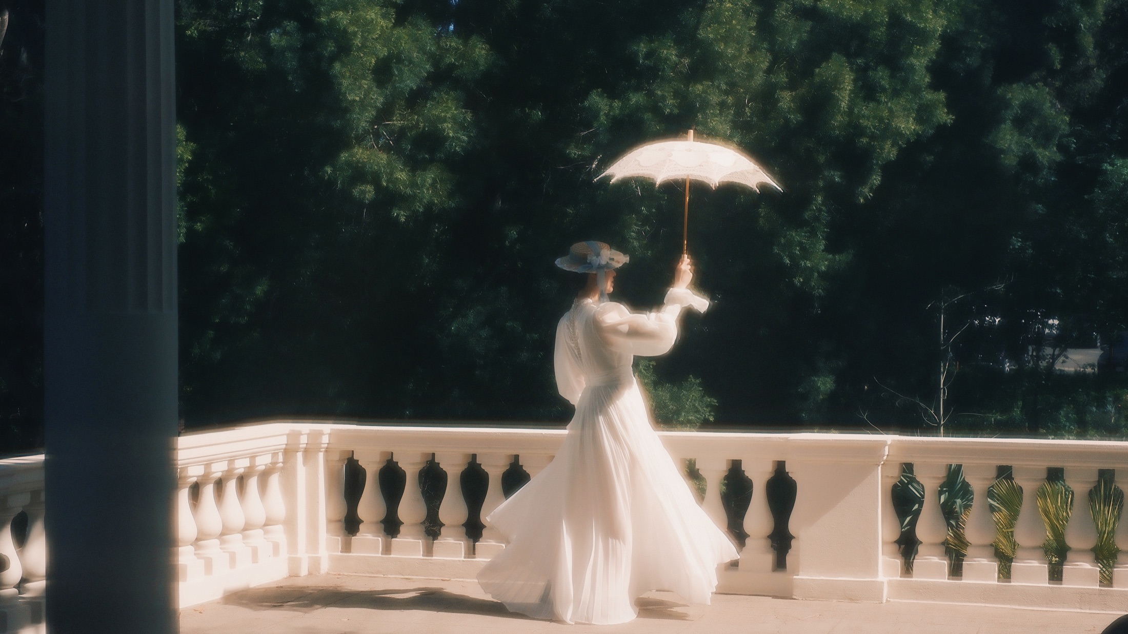 A wide dreamlike portrait of a woman in white with a parasol